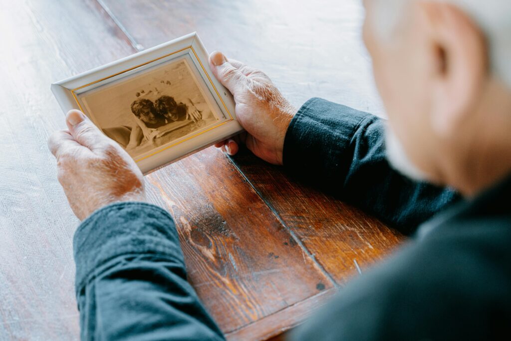 Elderly person holding family photograph, showing preserved older memories.