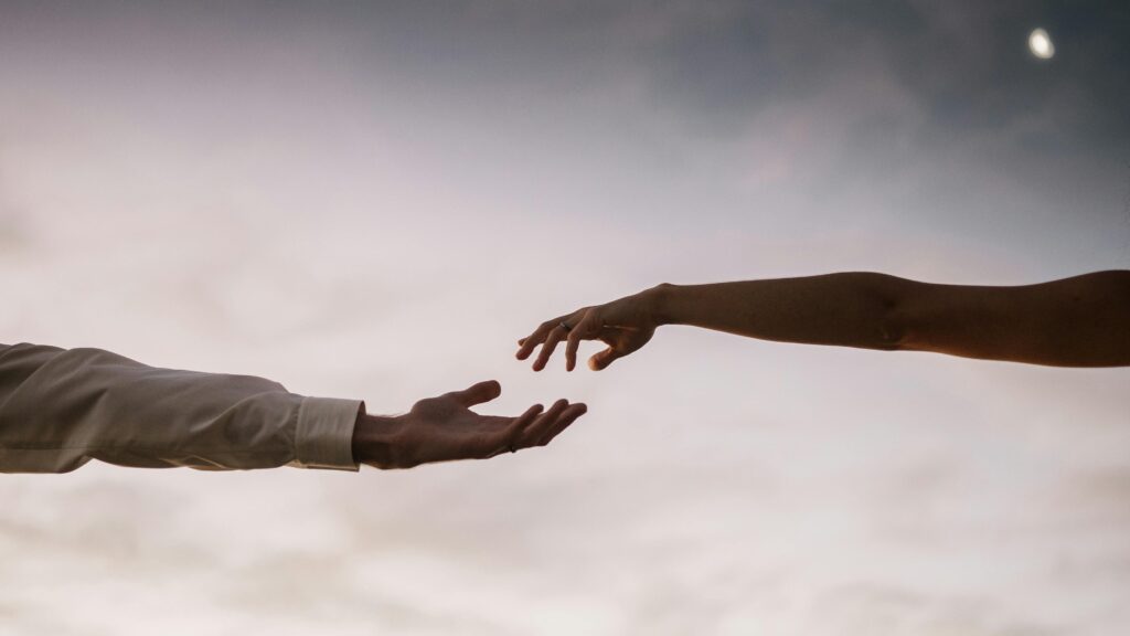 Two people reaching out with hands almost touching, symbolizing connection and the psychological effects of grief.