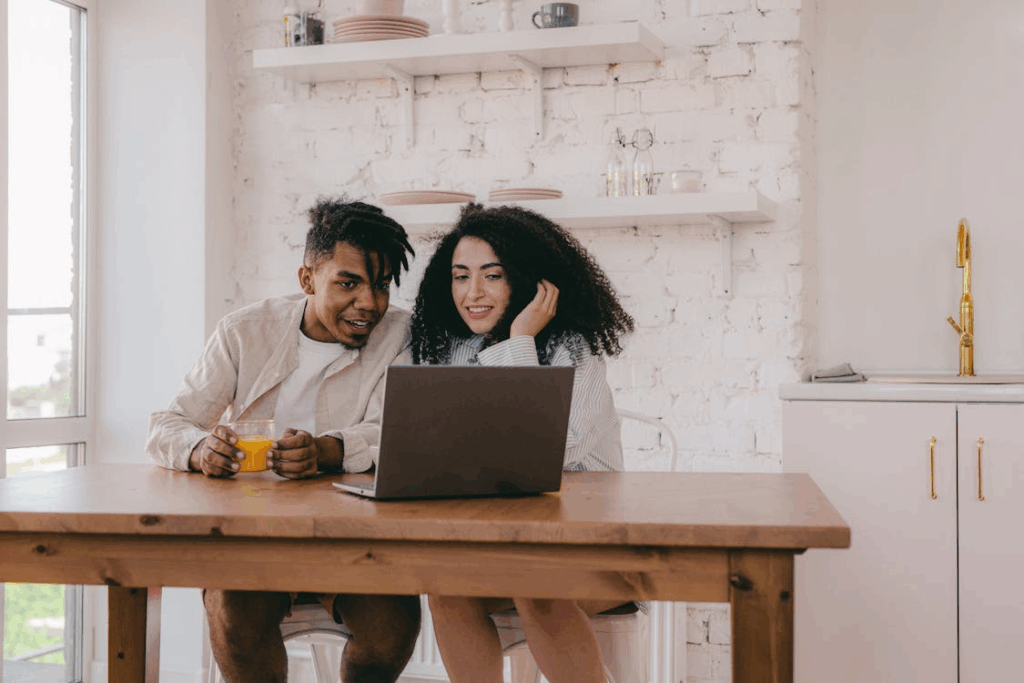 A Couple Sitting Looking at a Computer Laptop on a Wooden Table