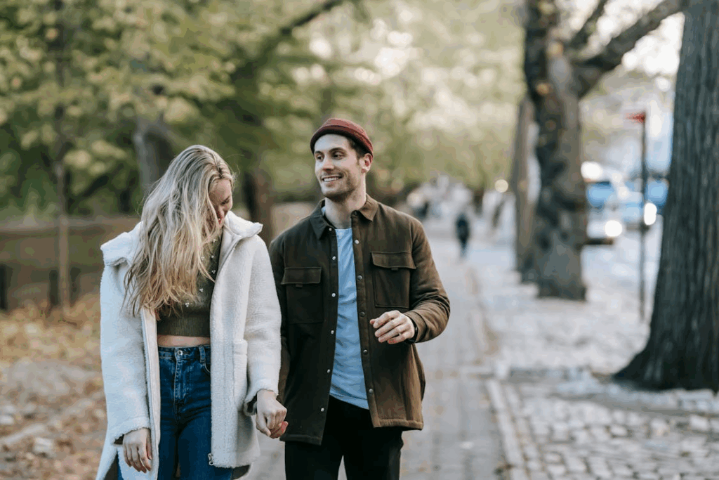 Stylish young couple holding hands and strolling on city street