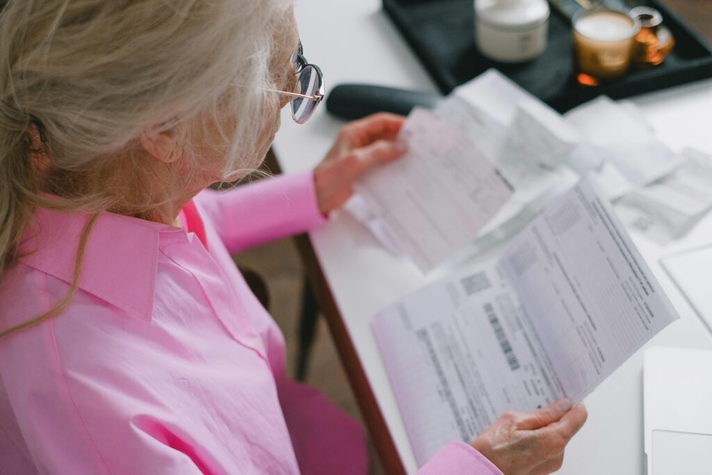 Elderly woman reviewing financial documents, showing how early signs of dementia affect money management.