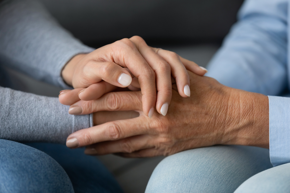 Close up granddaughter comforting grandmother, young woman daughter holding older mother hands, expressing love and support, good trusted family relationship, two generations, care to senior people