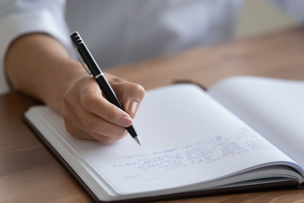 Crop close up of female nurse handwrite hospital patient anamnesis in medical journal at workplace, woman doctor or physician make notes fill clinic client information in paper book register