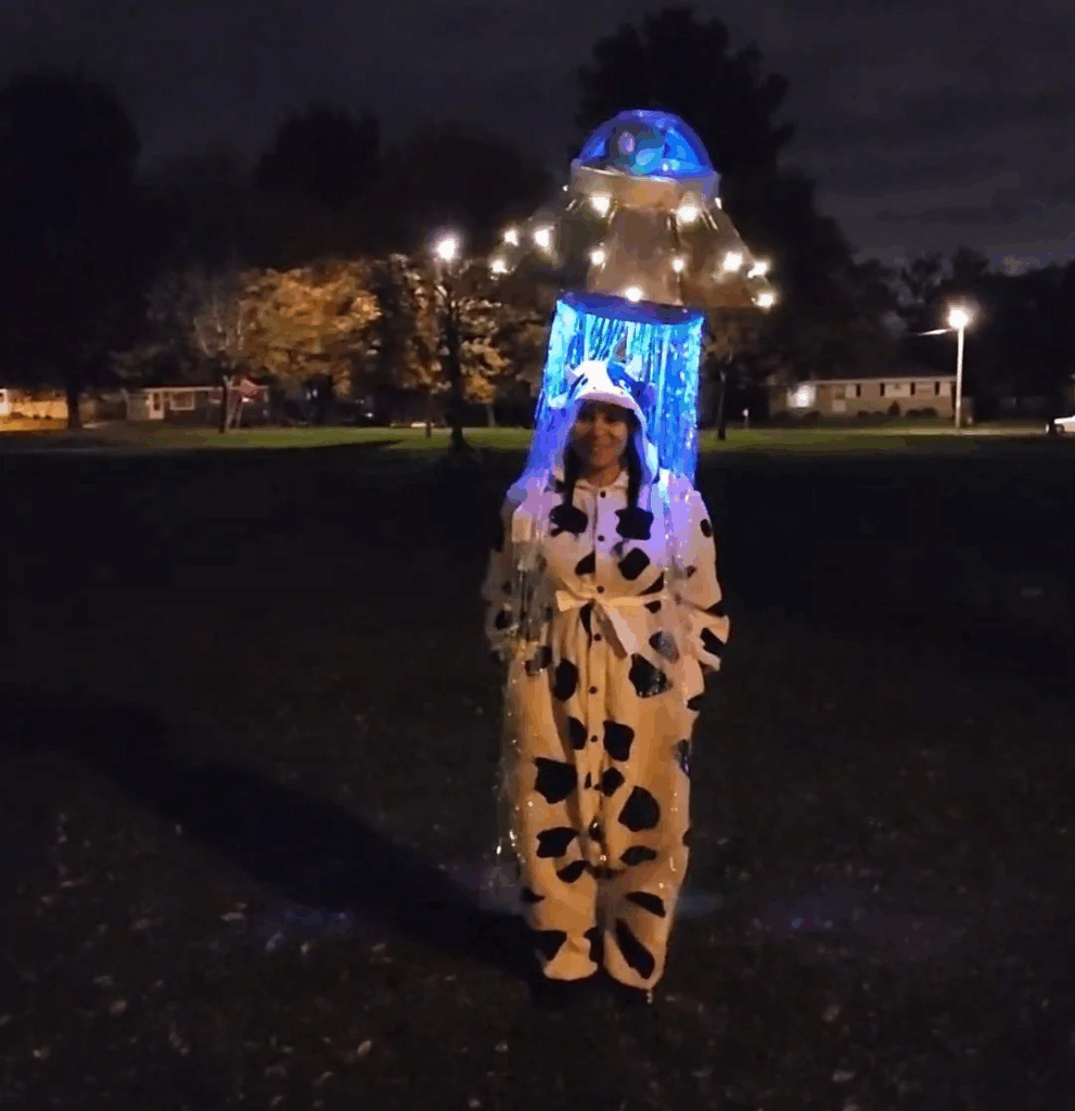 woman wearing cow onesie and a UFO light over her head