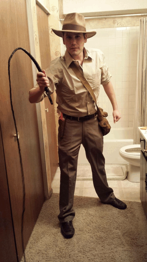 man wearing khaki shirt and pants with hat and whip in his hand