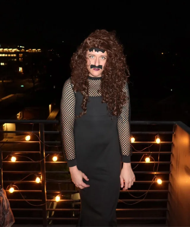 man wearing wig and dress with paper moustache
