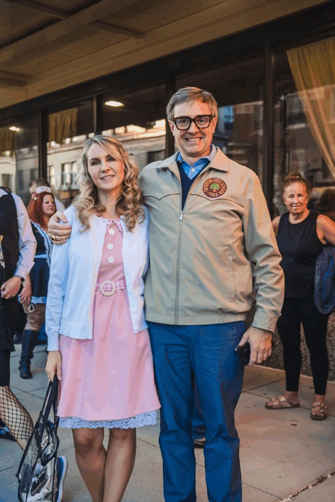 woman wearing pink dress standing next to man in blue pants
