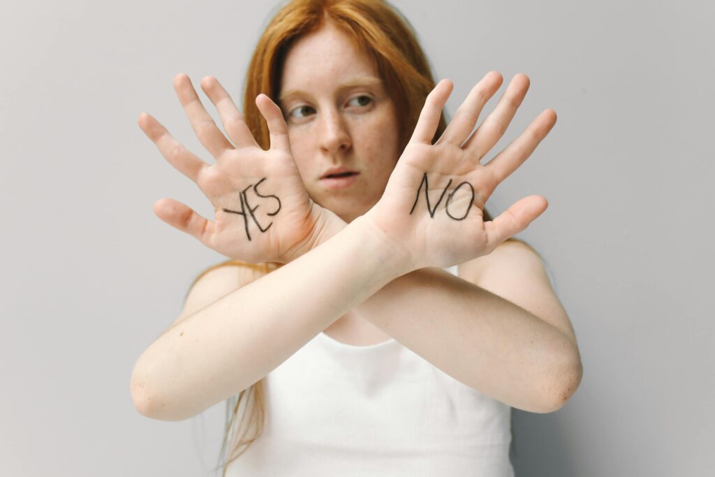Person with red hair holding up palms showing "YES" and "NO" written on them.