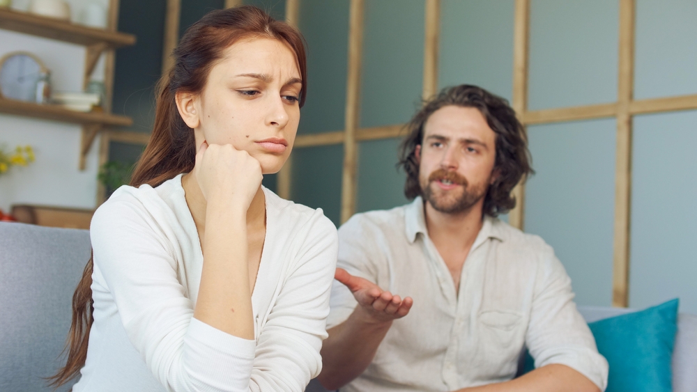 Couple Quarreling Sitting on the Couch at Home, Boyfriend Screams Accusing Girlfriend. Relationship Problems by Reason of Disagreement. The Man and Woman are Arguing. Young Woman Feeling Lonely.