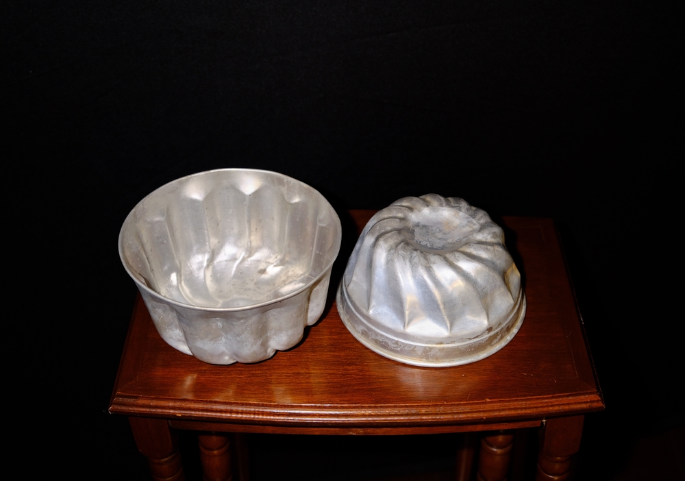 Two rustic jello moulds or molds on wood table with black background used for jelly or jello salads