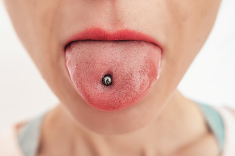 Woman's tongue with piercing. Cosmetology salon, open female mouth close-up.