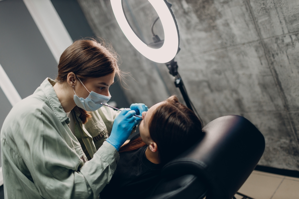 Young woman doing piercing at beauty studio salon