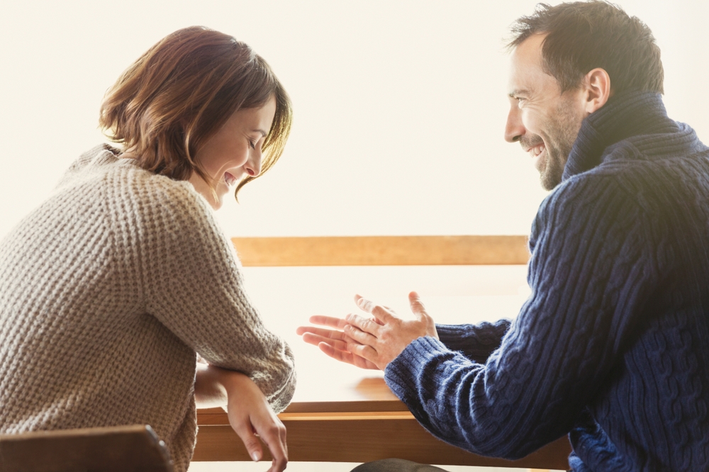 Laughing couple in sweaters at table