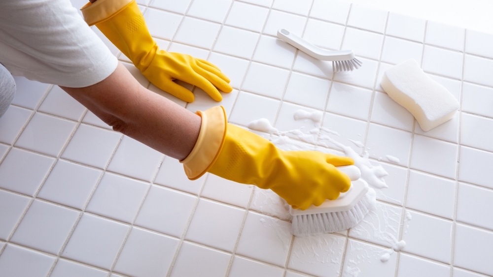 Hands of a woman cleaning bathroom tiles
