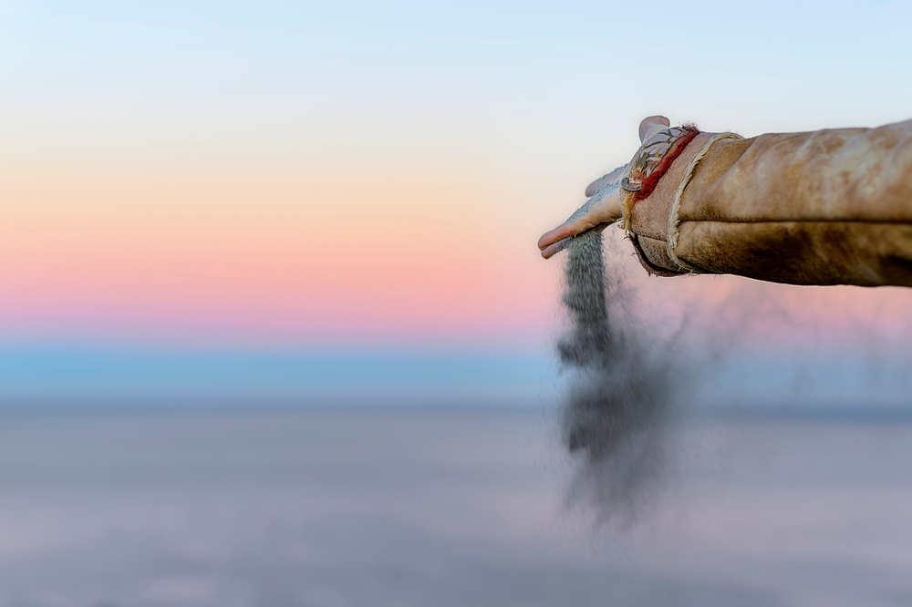 woman's hand spreads the ashes of a loved one to the wind over the sea