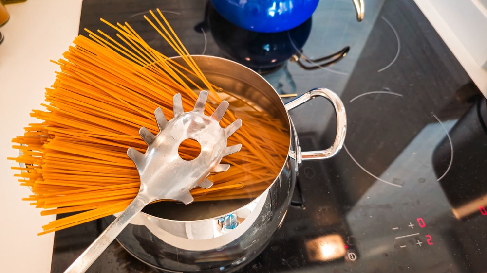 Spaghetti cooking in a steel pot on an induction electric stove