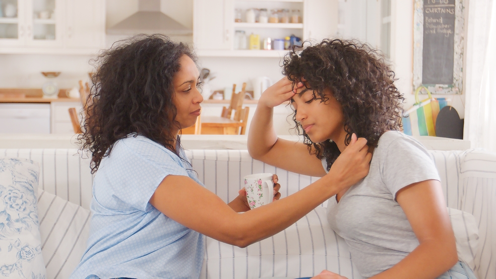 Mother Talking With Unhappy Teenage Daughter On Sofa
