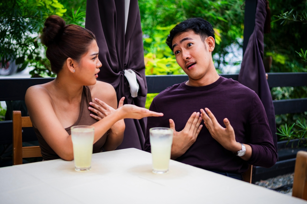 Angry girlfriend confronts her defensive boyfriend during a date at an alfresco cafe. Pent up frustration between a young couple.