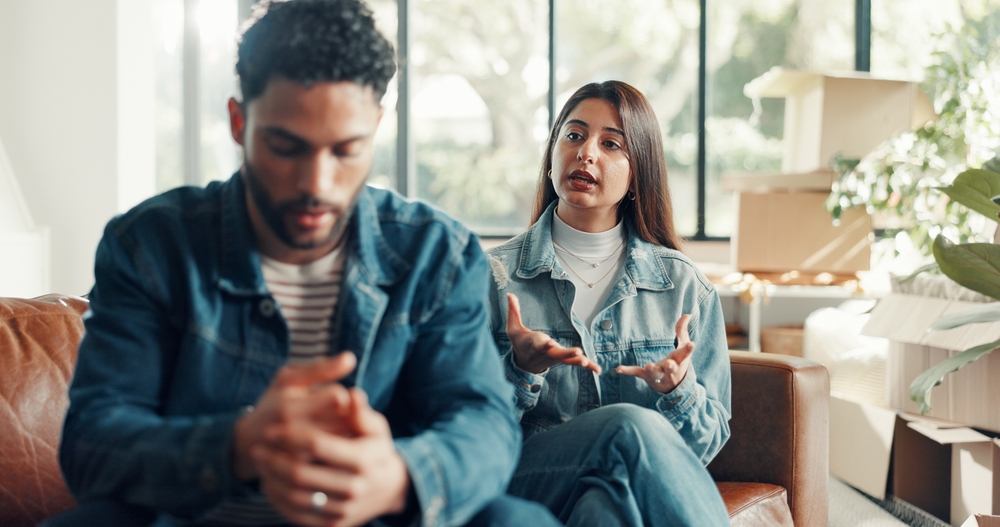 Couple, living room and conflict with moving, stress and drama in home or apartment. Frustrated, woman and man with dispute, angry and fight with relocation and anxiety or crisis with toxic partner
