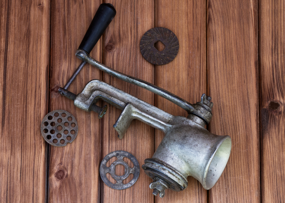Top view of vintage old mincer with different metal nozzle on wooden background