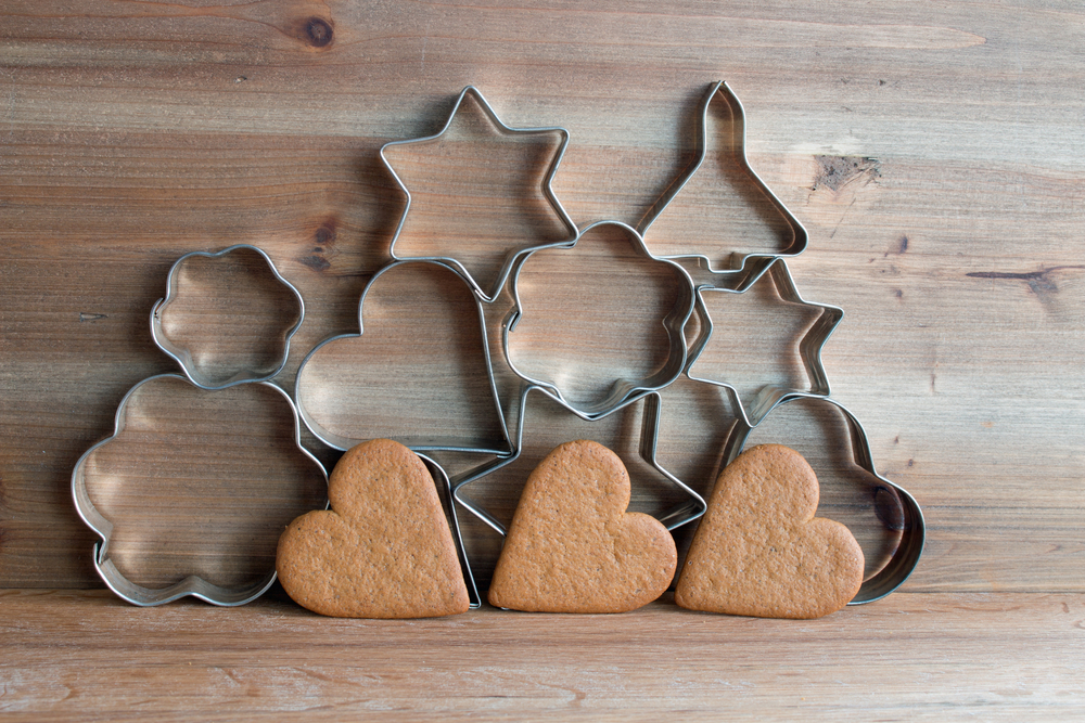 Christmas cookie cutters and gingerbread cookies on wooden background 
