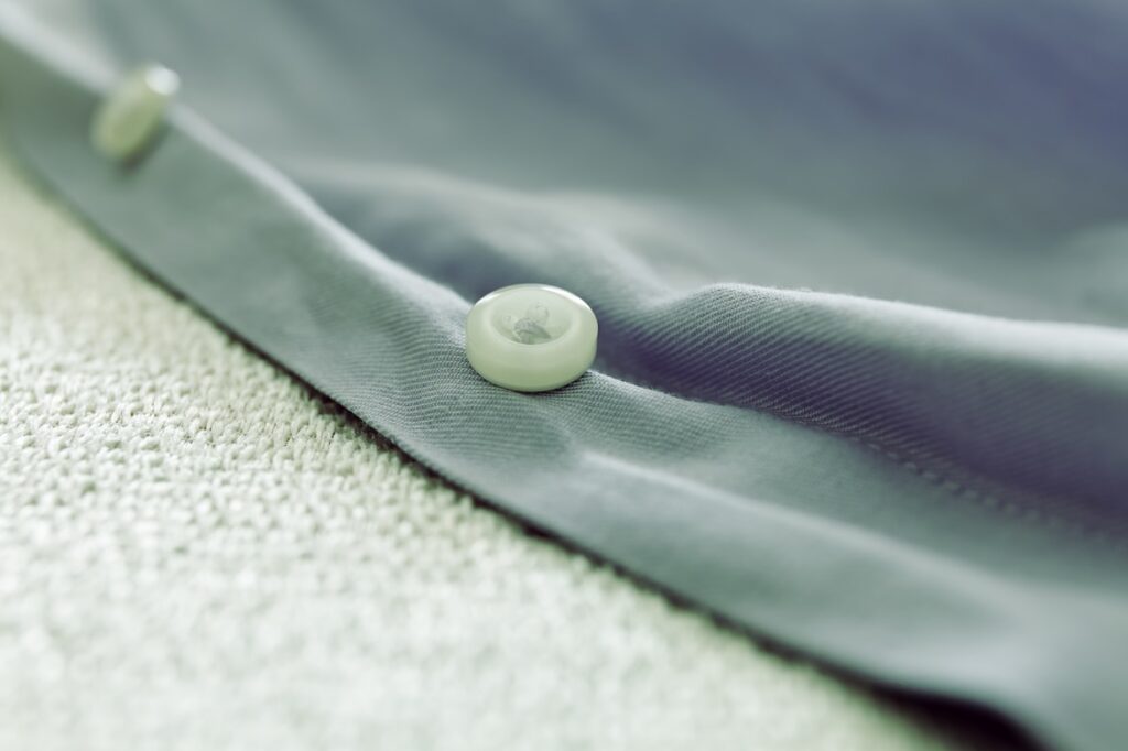 Close-up of a button on sage green fabric.