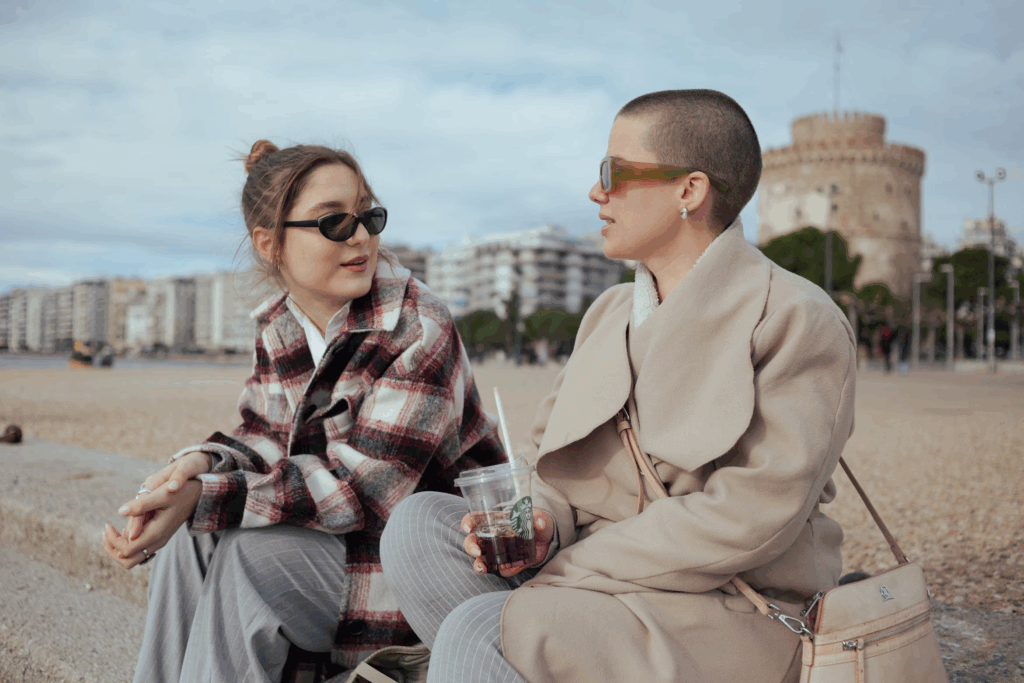 two friends sitting together talking while wearing sunglasses