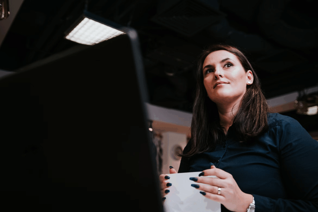 woman with black nails in office smiling and holding paper