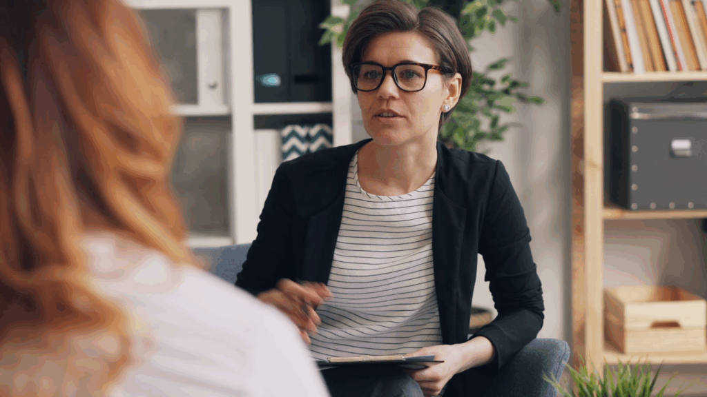 woman wearing glasses talking to other woman across from her