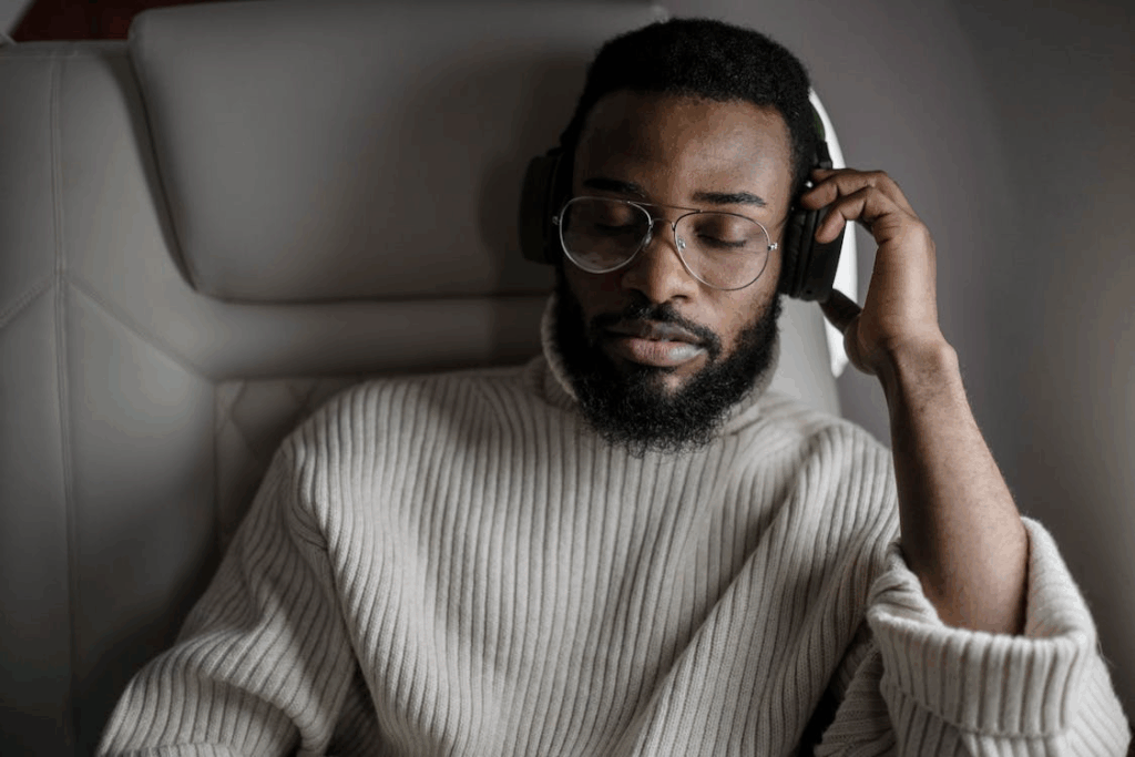 Man Wearing Beige Long Sleeves Shirt Listening to Music