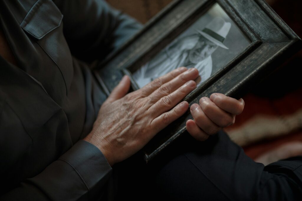 An older person's hands resting on a framed black-and-white photo.