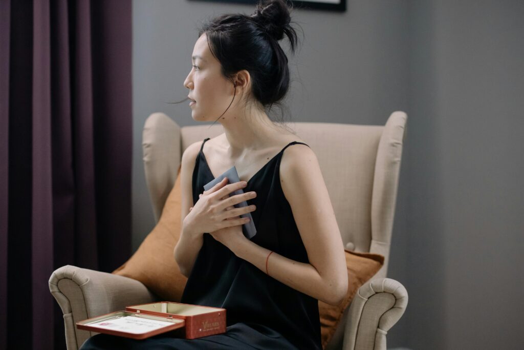 Woman sitting in a chair with her hand holding a letter on her heart, looking away.