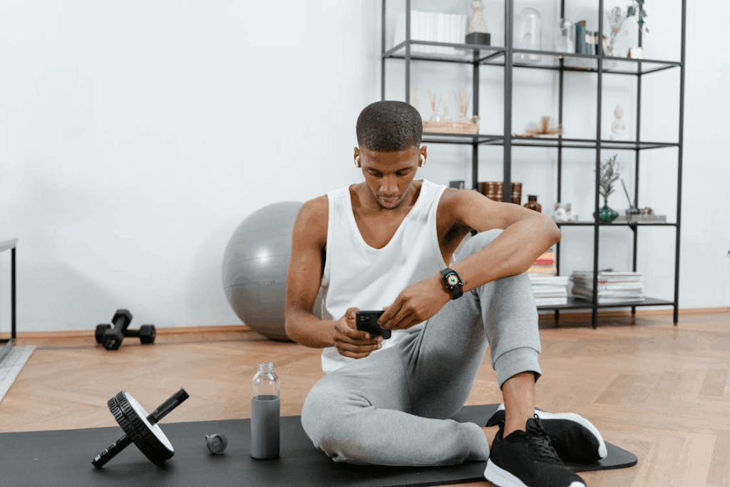 Man Sitting on a Yoga Mat Using a Smartphone