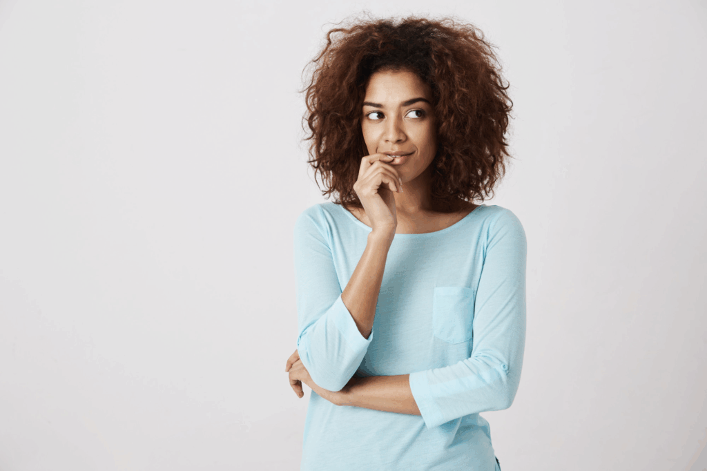 woman in blue shirt thinking against white wall
