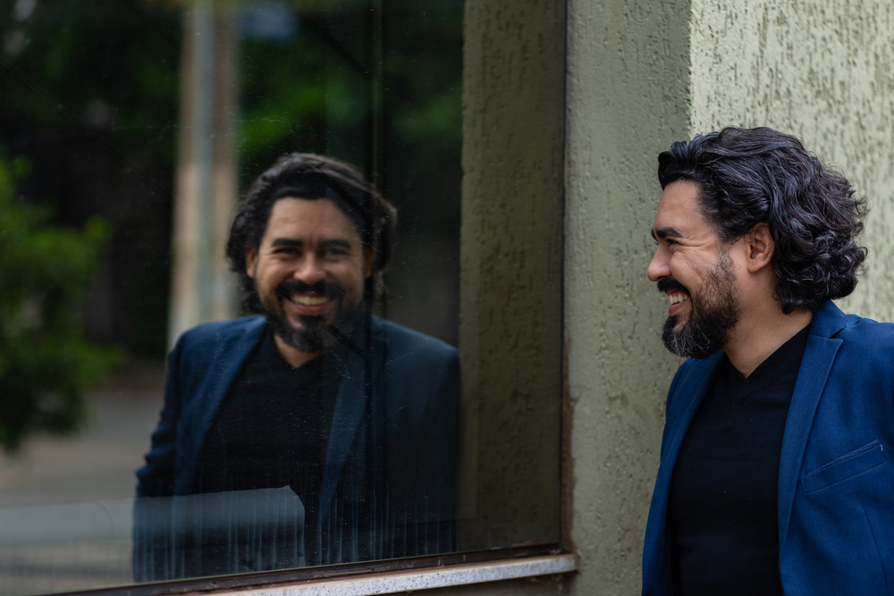 GOIANIA GOIAS BRAZIL - DECEMBER 13 2020: Elegant man smiling and looking at his own reflection in the building glass.
