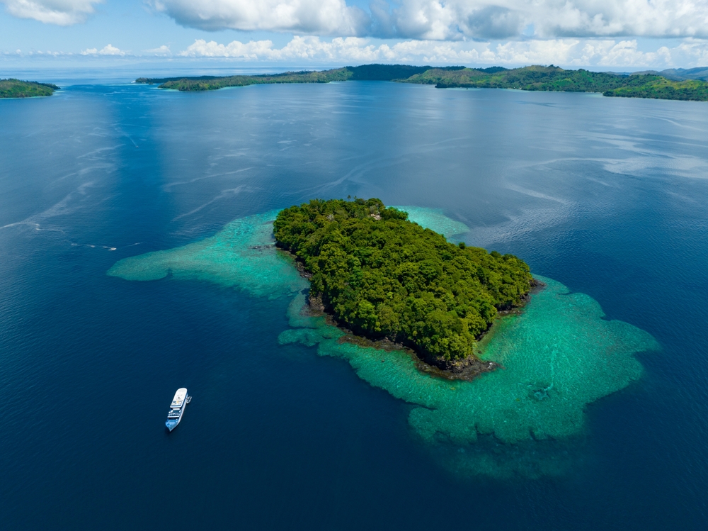 A beautiful coral reef surrounds a scenic island in the Solomon Islands. This beautiful country is home to spectacular marine biodiversity and many historic sites.
