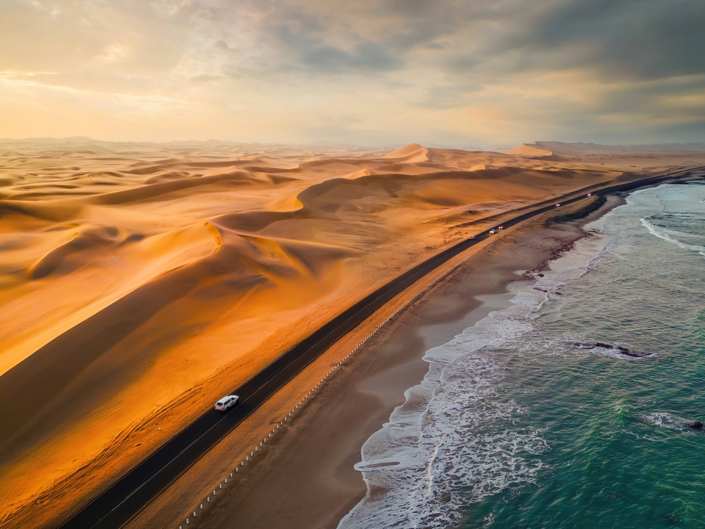 Aerial top view of street road with Namib Desert Safari, sand dune, coast sea in Namibia, South Africa. Natural landscape background at sunset. Famous tourist attraction. Sand in Grand Canyon
