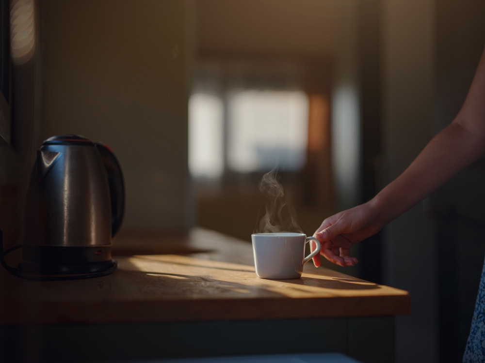 Woman is drinking coffee , morning routine. Tiny house. First property. Small apartment interior design. Minimalism. Moving in. Living alone. Charming trailer house with the morning sun