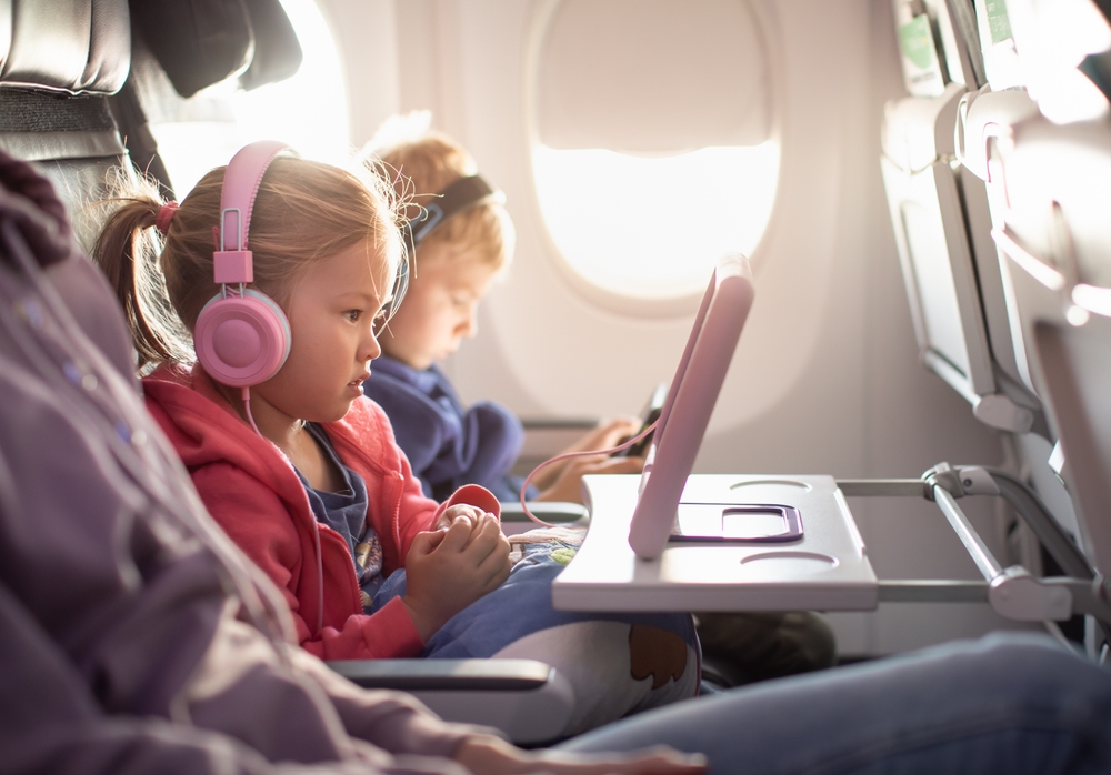 Adorable little boy girl travel by plane. Cute Kids sit at the window of an airplane and use a digital tablet during the flight. Family Traveling abroad with children