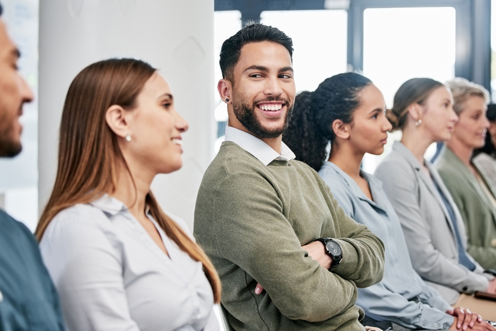 Businessman, smile or seminar with people in row for workshop, team building for corporate company. Male person, happiness or group for convention in conference room, staff at tradeshow or exhibition