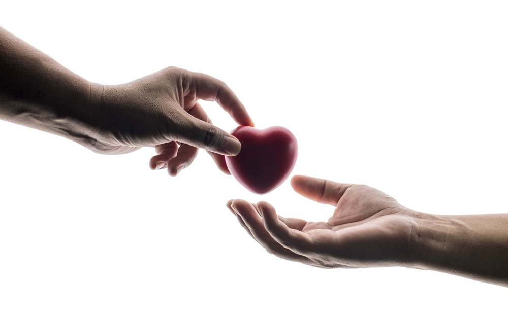 Adult hands giving a red heart, health care, organ donation, family life insurance, world heart day, world health day, praying concept