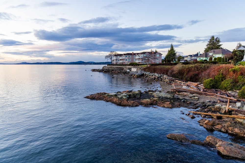 A tranquil sunrise paints the sky over Sidney, Vancouver Island, with serene waterfront views and coastal charm. The peaceful scenery showcases beautiful water and rocky shorelines in British Columbia