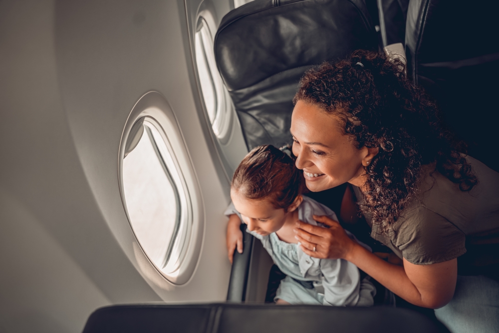 A truly joyful moment shared between a mother and her child as they both gaze out the airplane window during a flight