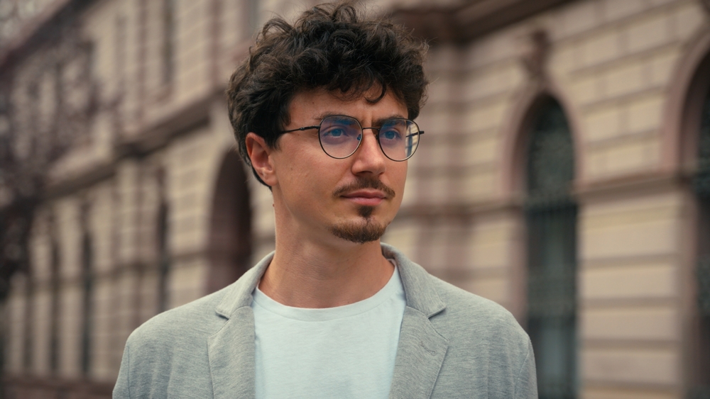 Close up portrait handsome European millennial pensive serious calm 30s guy in glasses looking around standing in city stylish business man confident businessman male outdoors travel posing at street