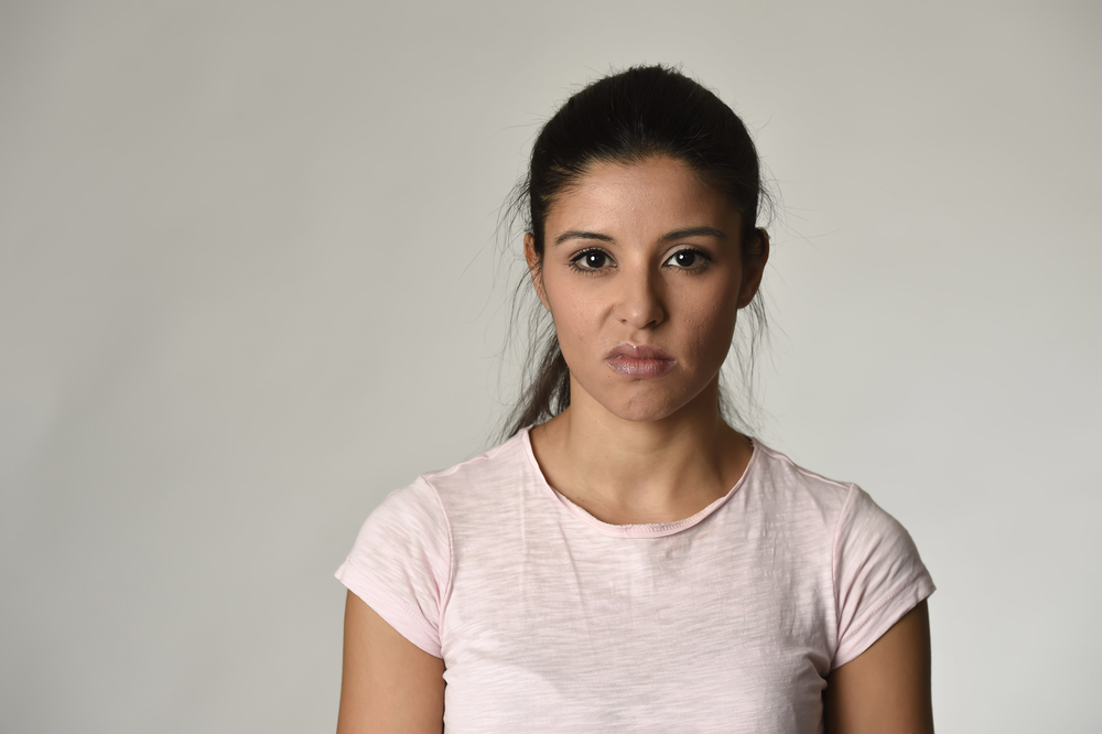 young beautiful arrogant and moody spanish woman showing negative feeling and contempt facial expression isolated on grey background looking cocky and defiant 