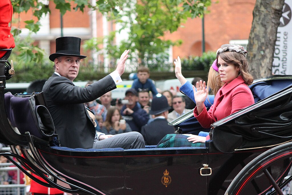 Prince Andrew in a top hat and Princess Eugenie in a bright pink outfit waving from an open carriage.