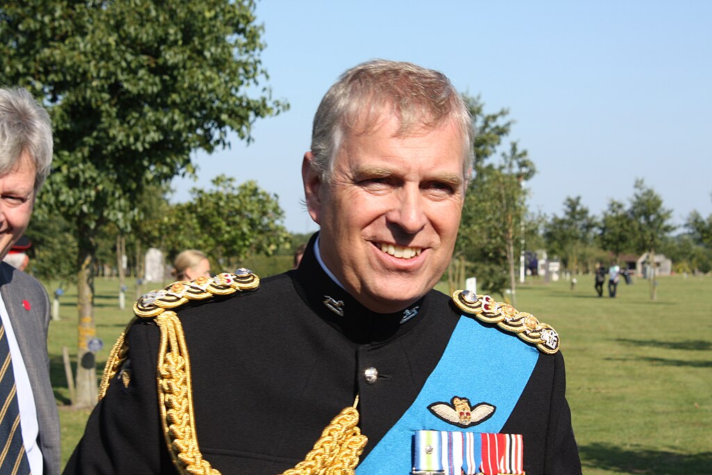 Prince Andrew smiling in military dress uniform with medals and a blue sash.