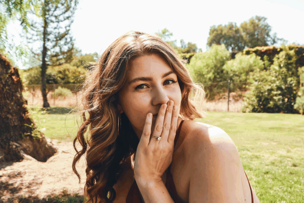 woman in park with hand over mouth