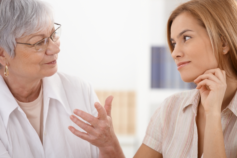 Senior mother and attractive daughter looking at each other with affection, talking, smiling.