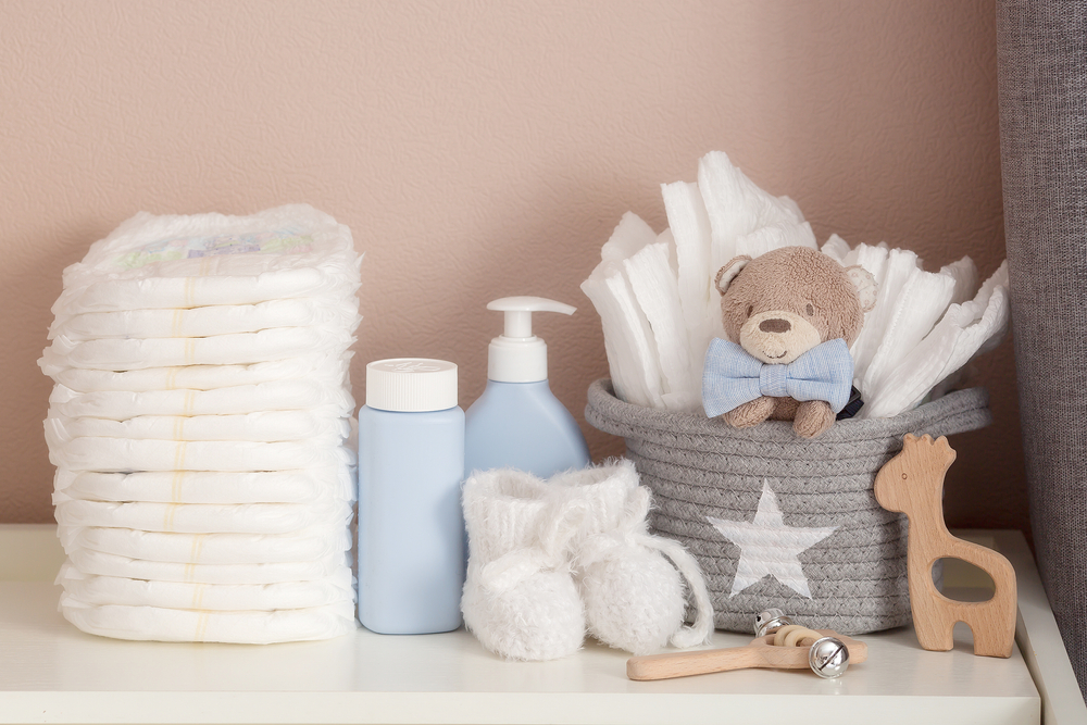 A stack of diapers, booties and baby accessories on a changing table. Copy space for text.